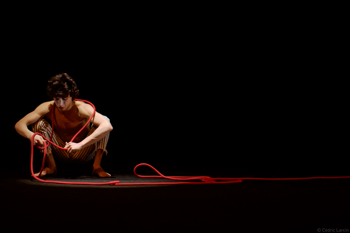 Garçon sur scène avec cordelette rouge